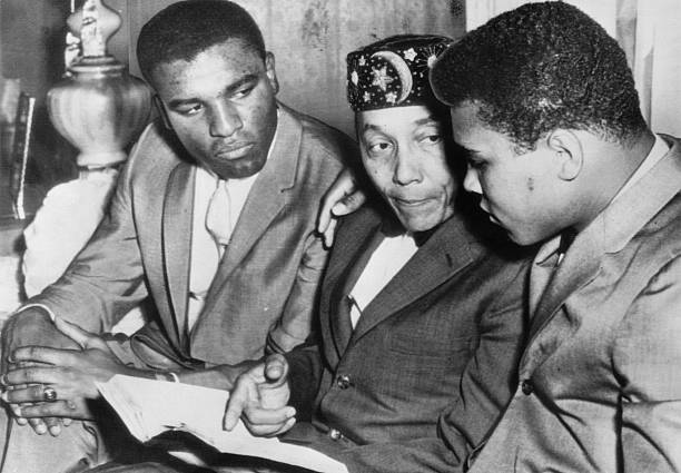 Heavyweight boxing champion Cassius Clay (R) and his brother Rudy (L) speaking with the leader of the Nation of Islam Elijah Muhammad Poole.